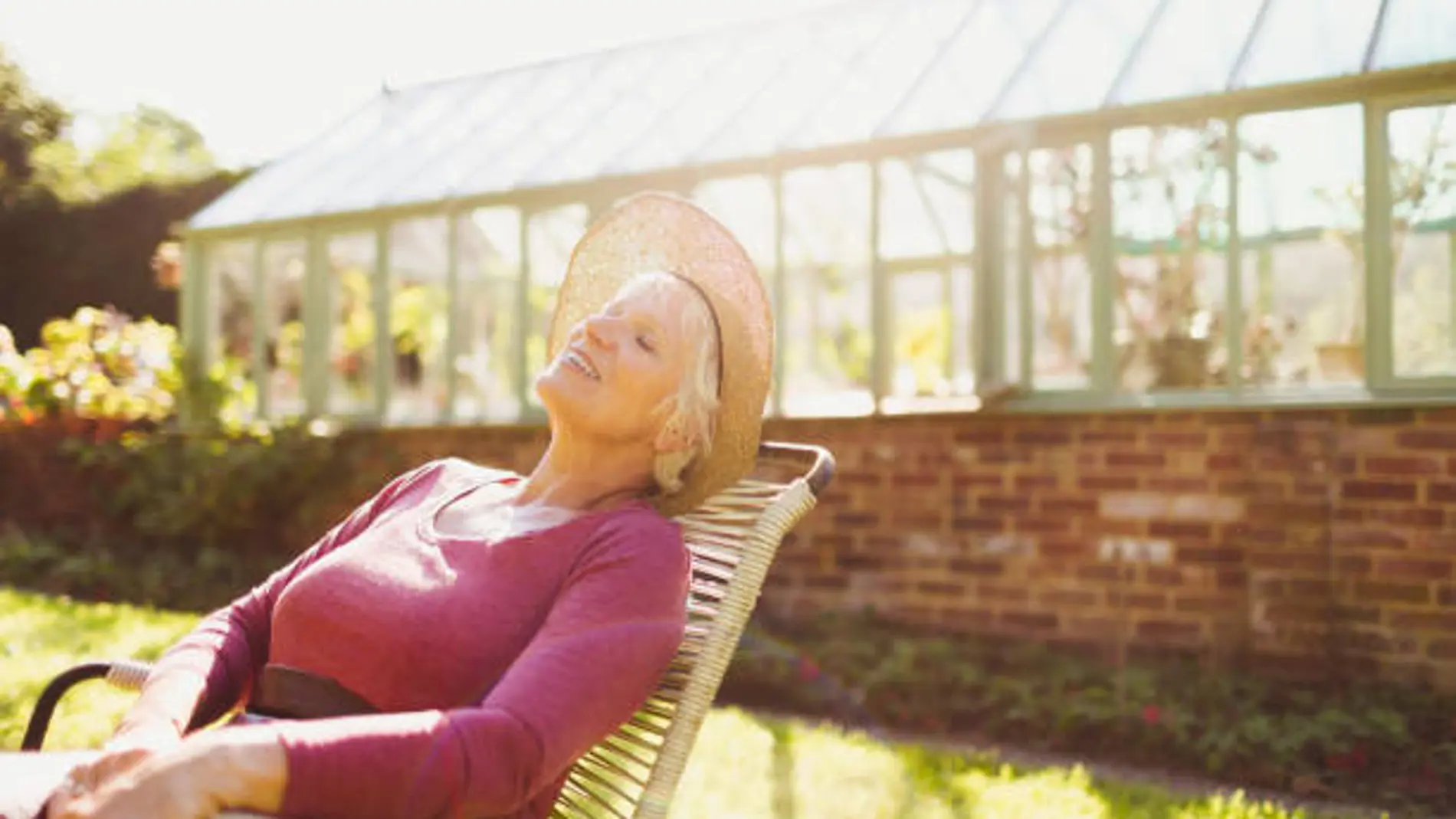 Una señora toma el sol en el jardín en una silla