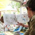 El líder del PP, Alberto Núñez Feijóo en una caseta infantil en la feria del libro contempla a su hijo al que le muestran los capítulos de un libro.