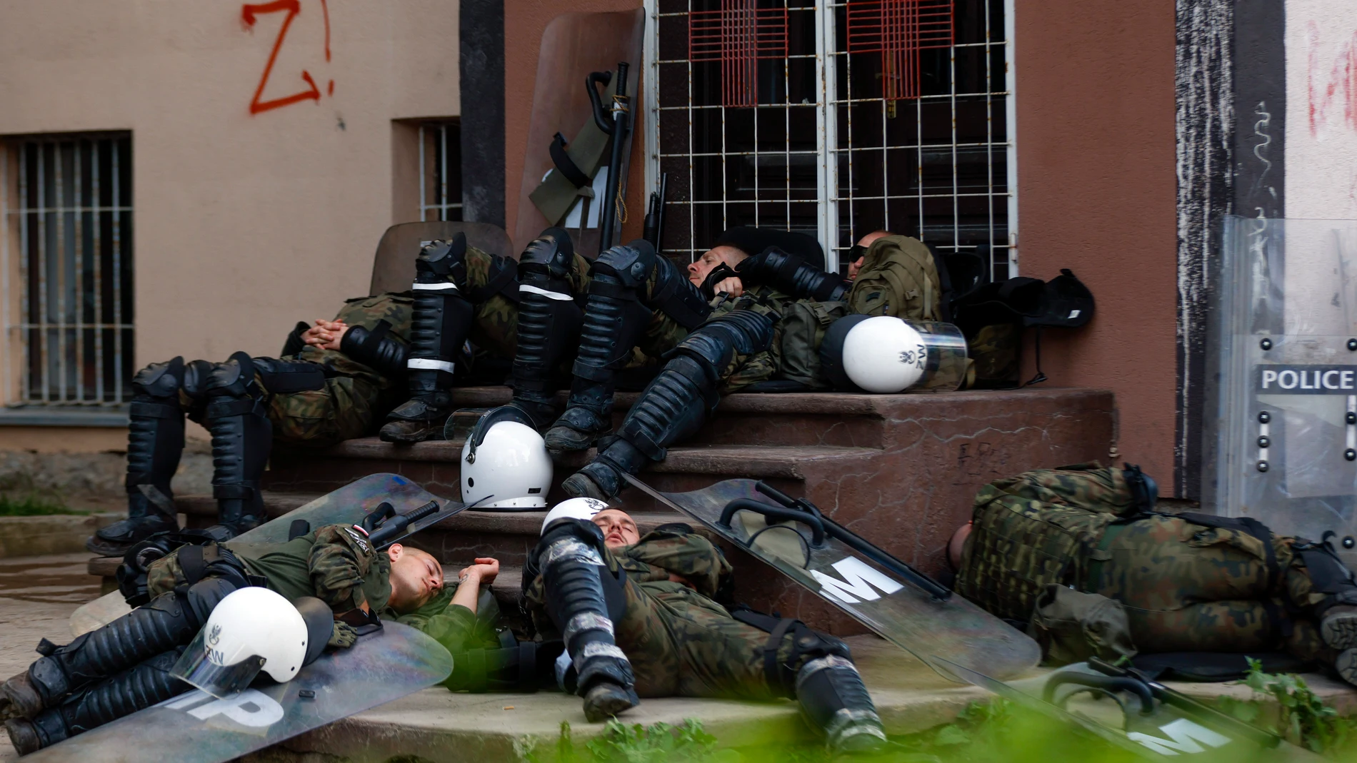 Polish soldiers, part of the peacekeeping mission in Kosovo KFOR, rest in front of a municipal building in the town of Zvecan, northern Kosovo, Tuesday, May 30, 2023. Troops from the NATO-led peacekeeping force in Kosovo have used metal fences and barbed wire to beef up positions in a northern town following clashes with ethnic Serbs that left 30 soldiers wounded. (AP Photo/Marjan Vucetic)