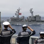 Marinos franceses del FS Lorraine saludan al paso del JS Yamagiri, buque de guerra japonés con la bandera del sol naciente