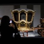 Una visitante observa uno de los carruajes exhibidos en la primera exposición temporal "En Movimiento. Vehículos y carruajes de Patrimono Nacional" que reúne un conjunto de obras que normalmente no se ven expuestas y que son, en muchos casos, únicas en el mundo, este miércoles en la Galería de Colecciones Reales en Madrid. 