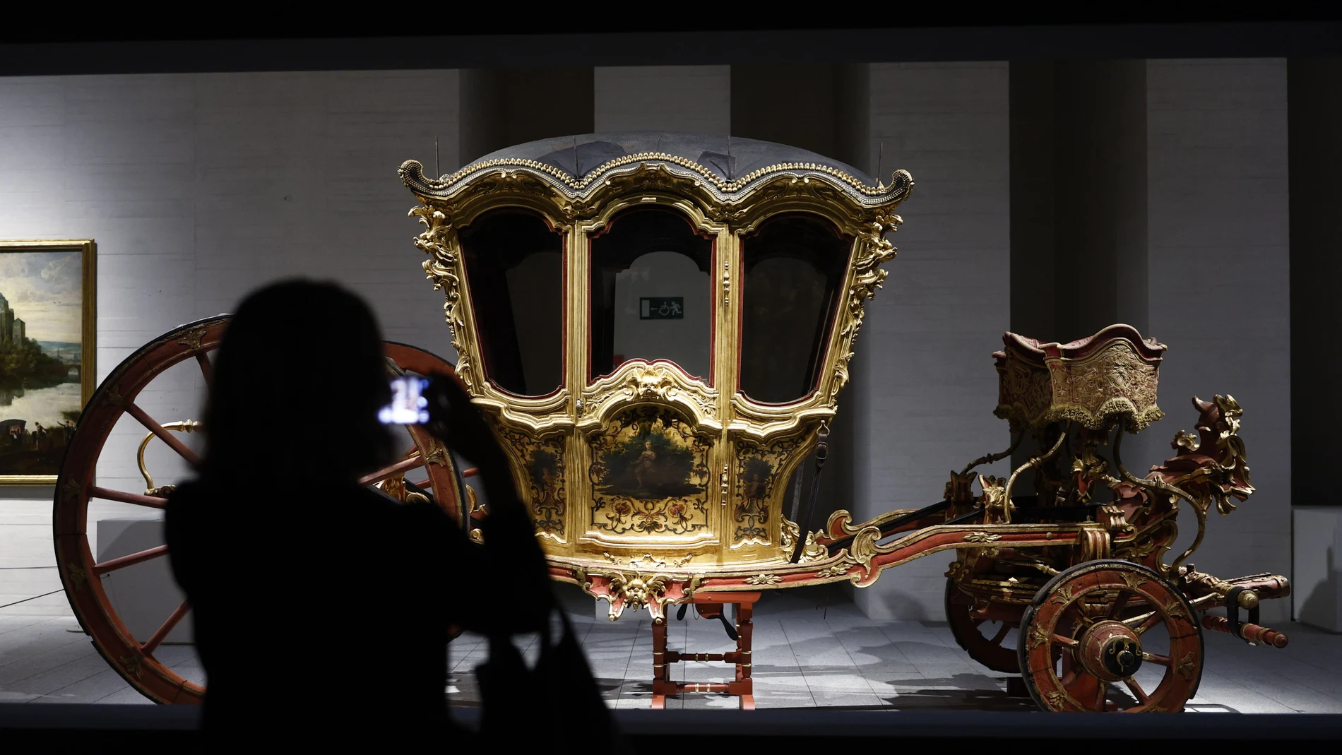 Una visitante observa uno de los carruajes exhibidos en la primera exposición temporal "En Movimiento. Vehículos y carruajes de Patrimono Nacional" que reúne un conjunto de obras que normalmente no se ven expuestas y que son, en muchos casos, únicas en el mundo, este miércoles en la Galería de Colecciones Reales en Madrid.