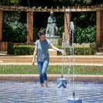 Una mujer se refresca en una fuente en plena ola de calor en Sevilla 