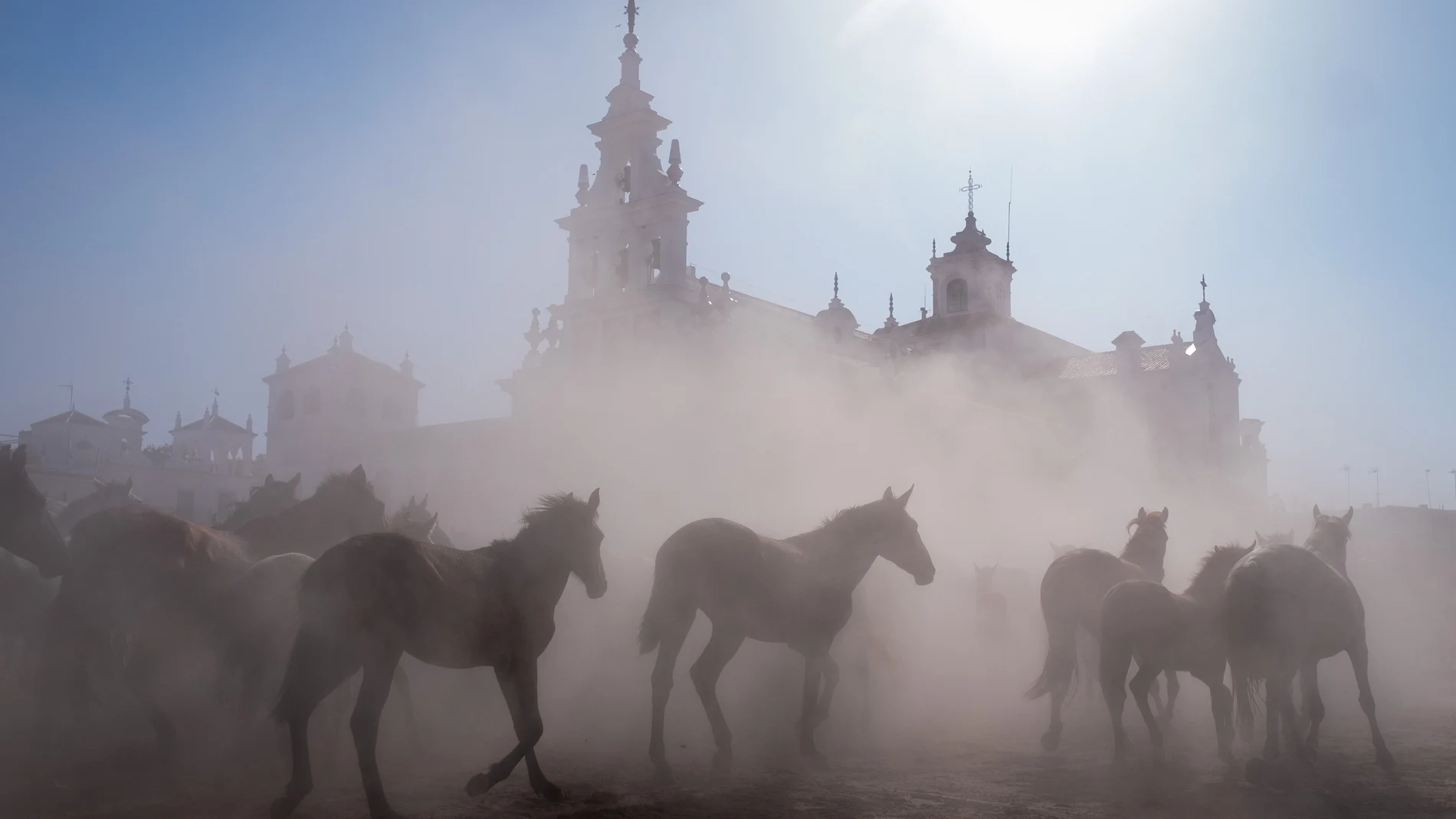 -FOTODELDÍA- EL ROCÍO (HUELVA), 26/06/2023.- Alrededor de 1.500 cabezas de equinos en estado semisalvaje pasan delante de la ermita de El Rocío (Huelva), tras salir esta mañana de la marisma de Doñana hasta los corrales del recinto ganadero municipal de Almonte, Huerta de la Cañada, en la conocida como 'Saca de las Yeguas', una tradición ancestral que los almonteños vienen realizando desde hace más de 500 años cada 26 de junio.