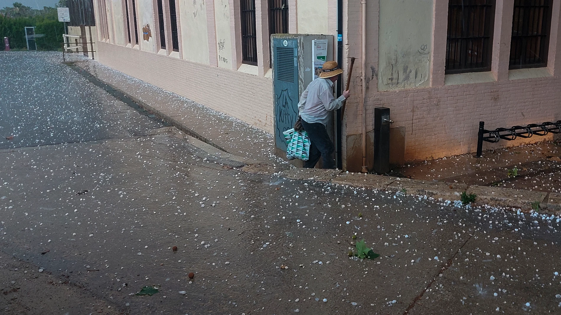 GODELLA (VALENCIA), 03/07/2023.- Un hombre busca resguardo ante la granizada que ha caido este lunes por la tarde en parte de la provincia de Valencia cuando Aemet ha emitido una alerta por tormentas en el interior y el litoral sur de Castellón y el interior y litoral norte de Valencia durante esta tarde, a partir de las 13 horas, y por lluvias acumuladas de hasta 40 l/m2 en el interior sur de Castellón y de 30 litros en Valencia. EFE/Kai Försterling