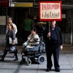 Una víctima de la talidomida muestra un cartel reclamando justicia