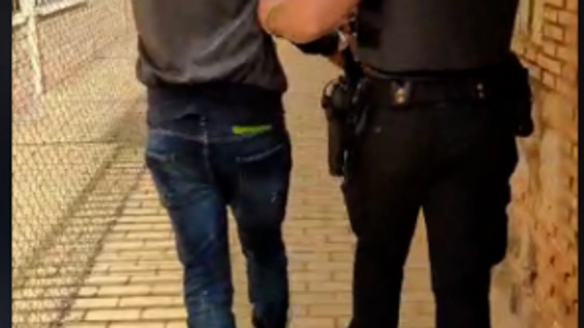 Uno de los detenidos es conducido por uno d elos agentes