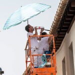  Unos trabajadores se cubren del sol con una sombrilla y beben agua en Andalucía