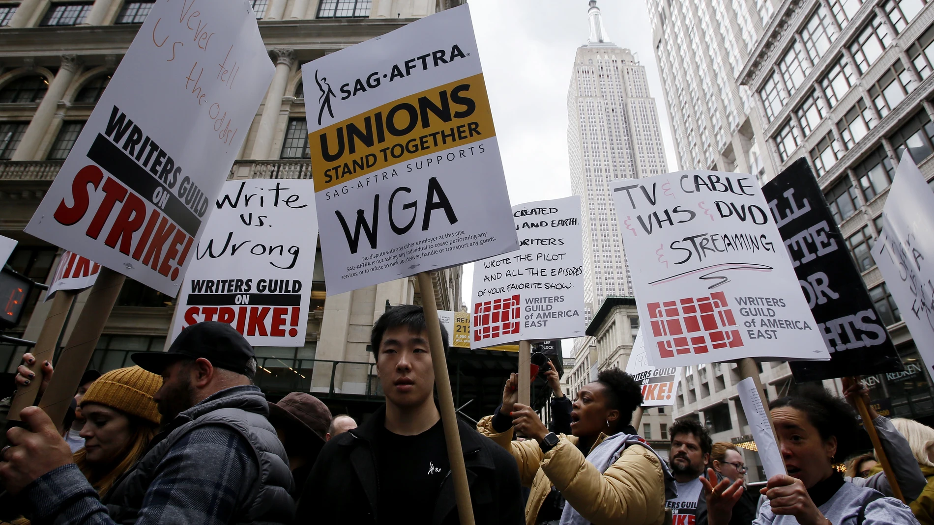 Demonstrators carry signs during a screenwriter's strike in New York City on May 2, 2023. - More than 11,000 Hollywood television and movie writers went on their first strike in 15 years Tuesday, after talks with studios and streamers over pay and working conditions failed to clinch a deal. The strike means late-night shows are expected to grind to a halt immediately, while television series and movies scheduled for release later this year and beyond could face major delays. (Photo by Leonardo Munoz / AFP)