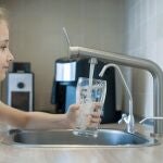Una niña se sirve un vaso de agua del grifo