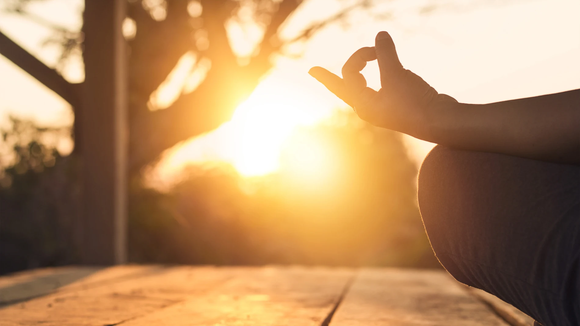 Mujer practicando yoga y meditación en posición de loto en la puesta de sol.