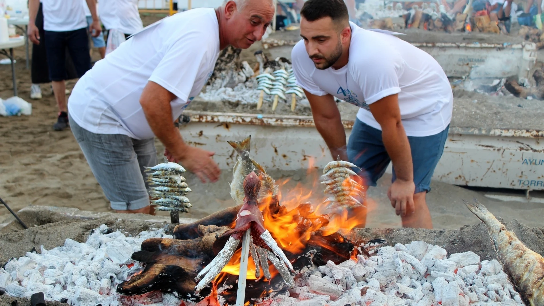 Dos espeteros contemplan las brasas en un chiringuito de la Costa del Sol