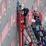 People carrying bags are seen walking up the gang-way into the Bibby Stockholm accommodation barge, moored to the quayside at Portland Port in Portland, on the south-west coast of England on August 7, 2023.