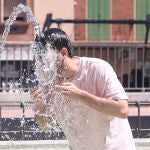 Un joven se refresca en una fuente durante una ola de calor