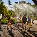 Un grupo de turistas pasa junto a unos aspersores de vapor de agua
