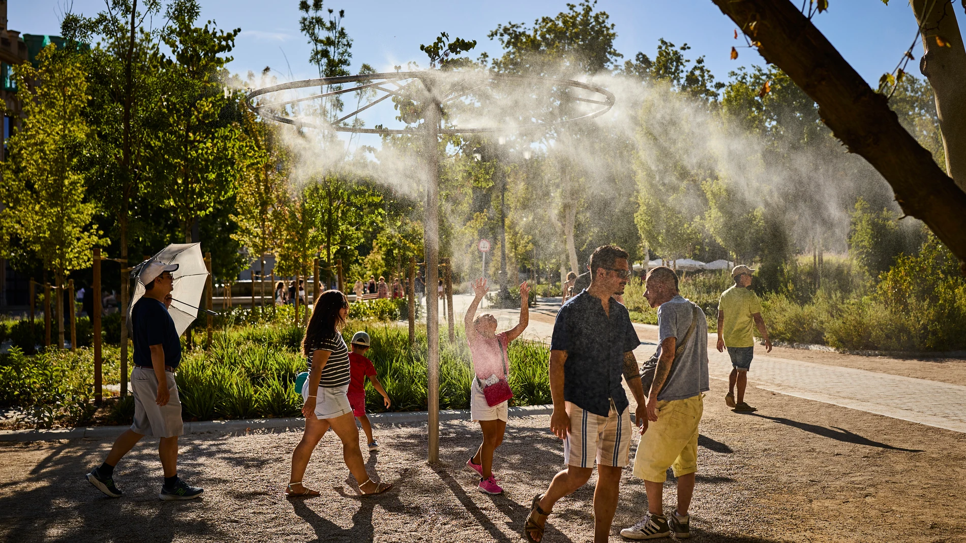 Un grupo de turistas pasa junto a unos aspersores de vapor de agua