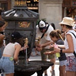 Varias personas se refrescan en una fuente de Barcelona durante una ola de calor