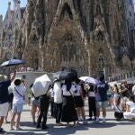 Varios turistas equipados con sombrillas visitan la Sagrada Familia, en Barcelona.