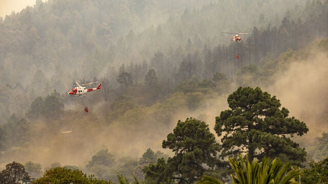 Dos helicópteros trabajan este viernes en las tareas de extinción del incendio en Candelaria (Santa Cruz de Tenerife) que ha arrasado 14.571 hectáreas, el mayor incendio forestal este año en España. Este enorme incendio ya tiene el perímetro consolidado con puntos calientes en la zona norte