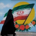 Mujer paseando frente a la bandera de Irán