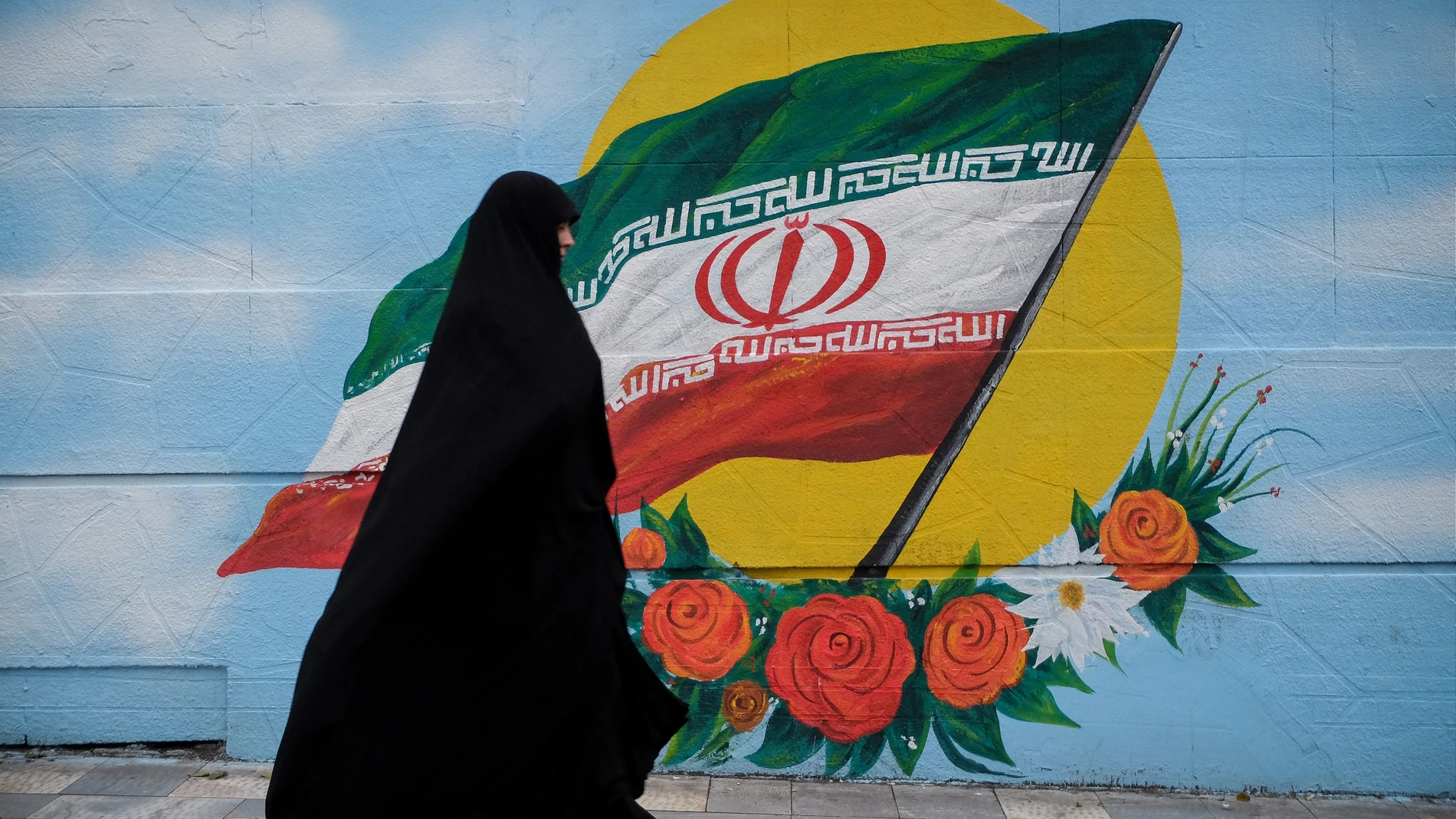 Mujer paseando frente a la bandera de Irán