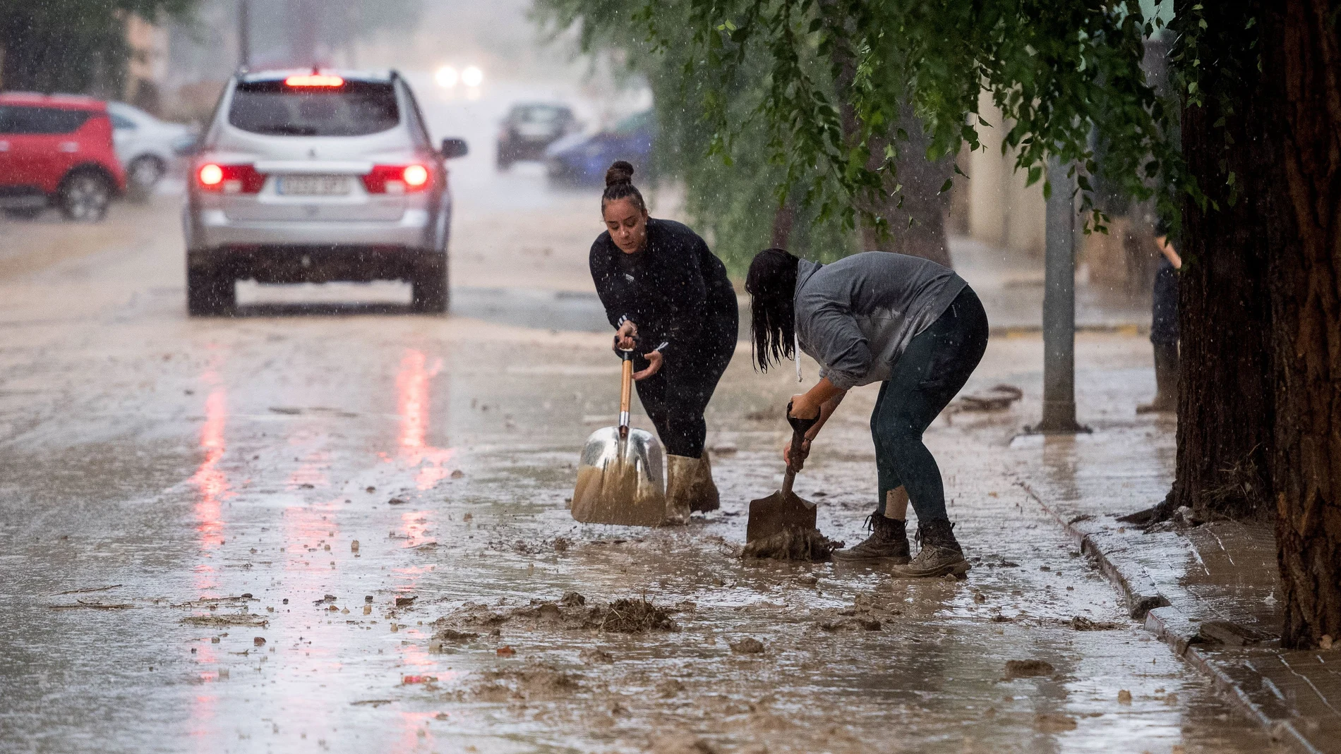 Varias personas retiran el lodo acumulado en Magán (Toledo) a causa de las fuertes lluvias