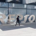Una mujer camina frente a las letras Repsol en su sede, en Madrid (España). 