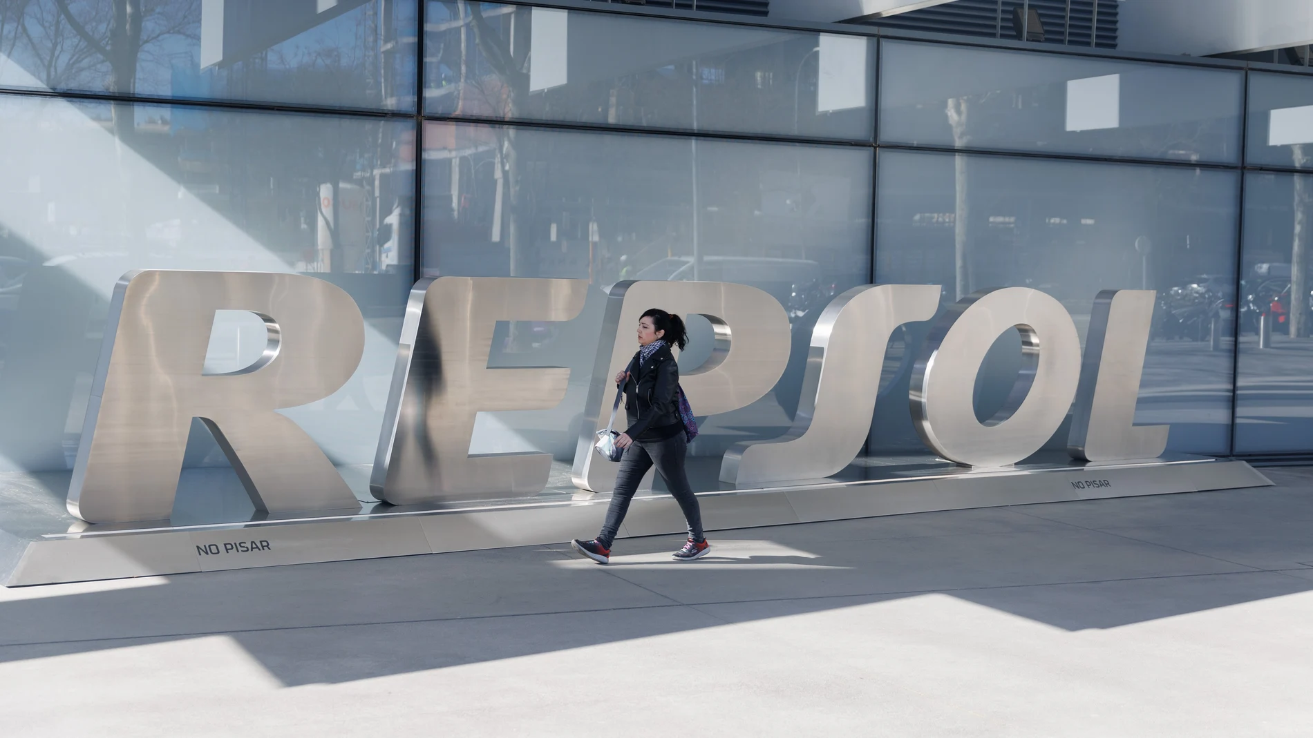 Una mujer camina frente a las letras Repsol en su sede, en Madrid (España).