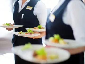 Imagen de archivo de dos camareras con platos sobre sus manos Imagen de archivo de dos camareras con platos sobre sus manos