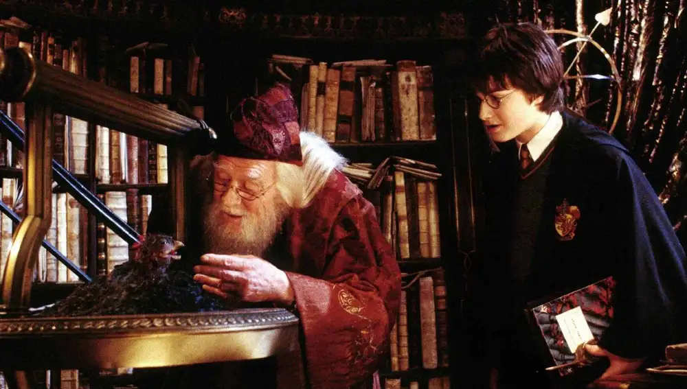 El actor Daniel Radcliffe (R) interpreta a Harry Potter mientras observa cómo el Profesor Dumbledore, interpretado por el fallecido Richard Harris, alimenta a Fawkes, el Fénix, en "Harry Potter y la cámara secreta"
