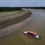 A fisherman stands on his boat as he navigates near thousands of dead fish awash on the banks of Piranha Lake due to a severe drought in the state of Amazonas, in Manacapuru, Brazil, Wednesday, Sept. 27, 2023. (AP Photo/Edmar Barros)
