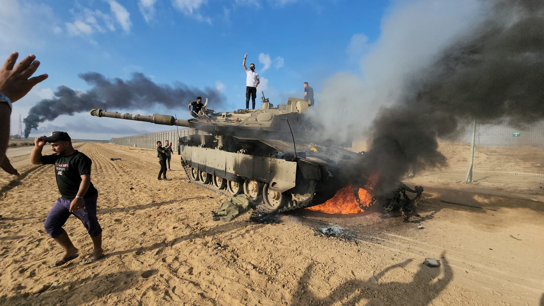 Palestinos celebran junto a un tanque israelí destruido en la valla de la Franja de Gaza, al este de Khan Younis