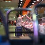 Mujer pagando en una carnicería de un mercado 