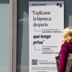 Una mujer ante un cartel bancario sobre las hipotecas.