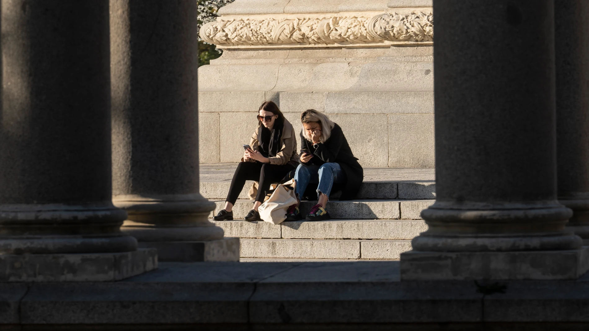 Dos jóvenes miran su móvil en El Retiro
