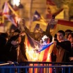 Decenas de manifestantes queman una bandera estelada, durante una manifestación contra la amnistía frente a la sede del PSOE en Ferraz.