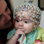 Bebé usando un casco de EEG para el estudio. Fotografiado con su madre. (University of Birmingham.) 