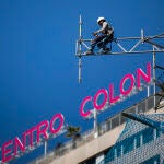 Imagen de unos operarios desmontando andamios en la Torre Colon con la letras del edificio Centro Colon a la espalda.