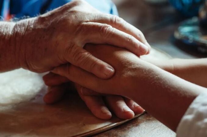 Manos de persona mayor y persona joven entrelazadas Manos de persona mayor y persona joven entrelazadas