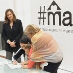Una madre con su bebé en brazos firma el contrato de alquiler en presencia de la alcaldesa