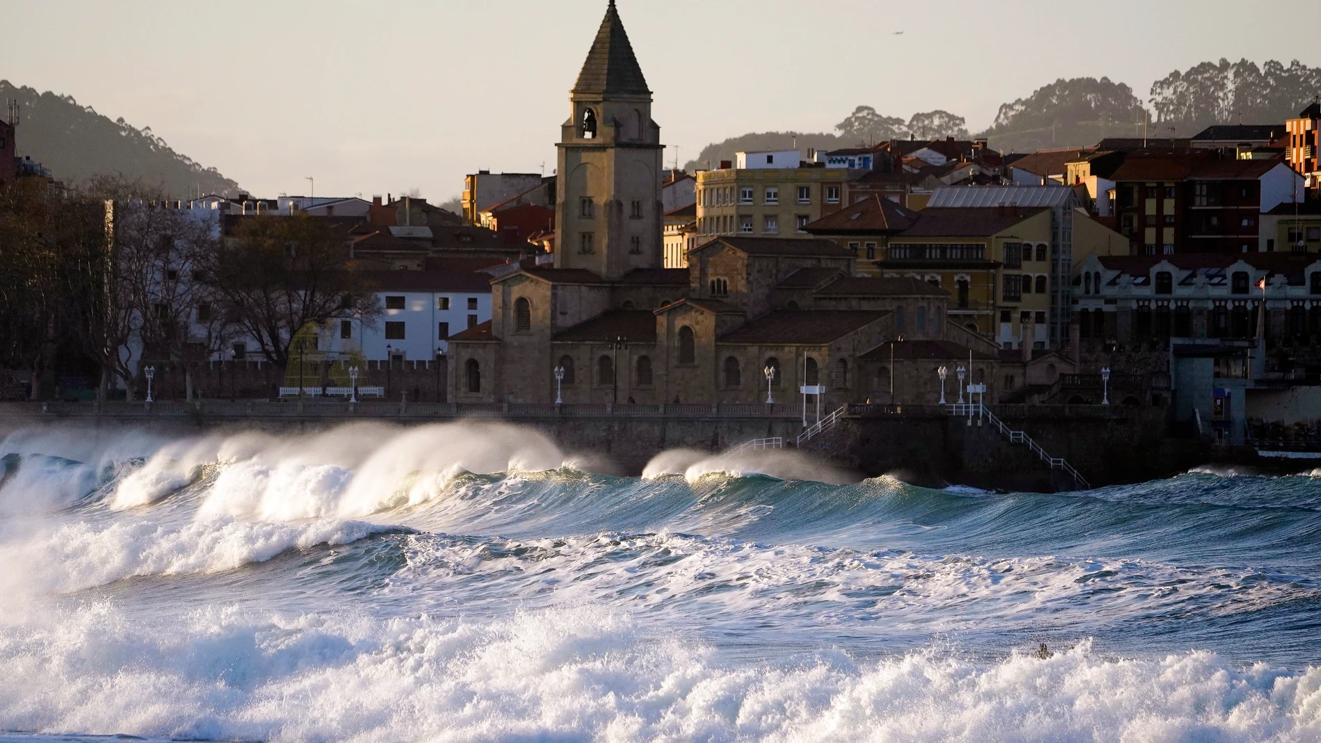 -FOTODELDIA- GIJÓN, 16/12/2023.- Oleaje en la Playa de San Lorenzo con la iglesia de San Pedro al fondo este sábado en Gijón. La Agencia Estatal de Meteorología (Aemet) prevé este sábado, en Asturias: intervalos de nubes bajas al principio del día, tendiendo a cielo poco nuboso o despejado. Temperaturas mínimas con pocos cambios en la cordillera y en descenso, que podrá ser localmente notable, en el resto; máximas con cambios ligeros, salvo en la cordillera, donde se producirán ascensos notab...