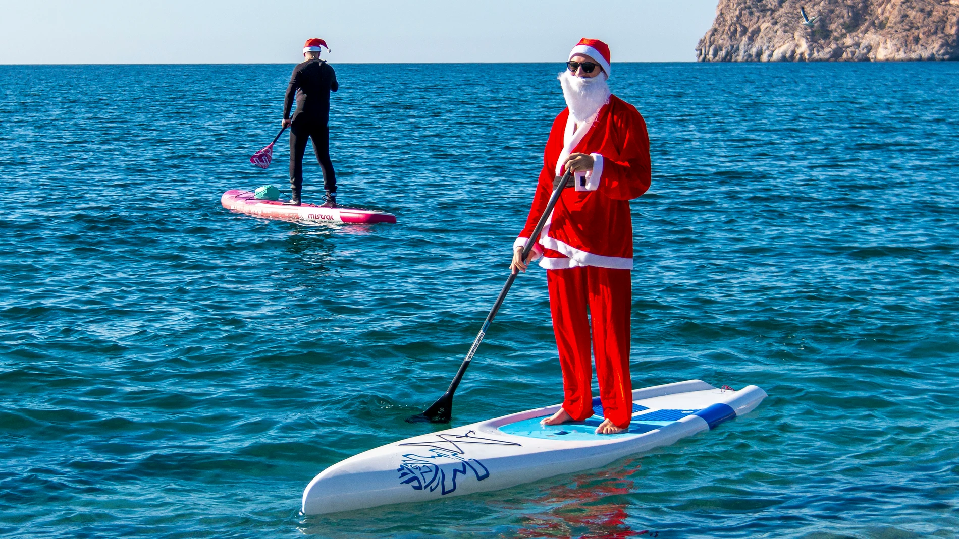 LA HERRADURA (GRANADA), 23/12/2023.- Una "cabalgata" de más de medio centenar de personas de distintos puntos de Andalucía y ataviadas como Papá Noel han atravesado con sus tablas de paddle surf y kayak la Bahía de la Herradura, en la costa Tropical de Granada, y de esa forma celebrar la Navidad. EFE/ Alba Feixas