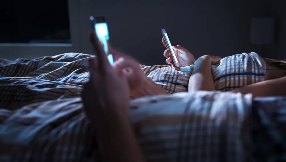 Pareja mirando el teléfono móvil en la cama