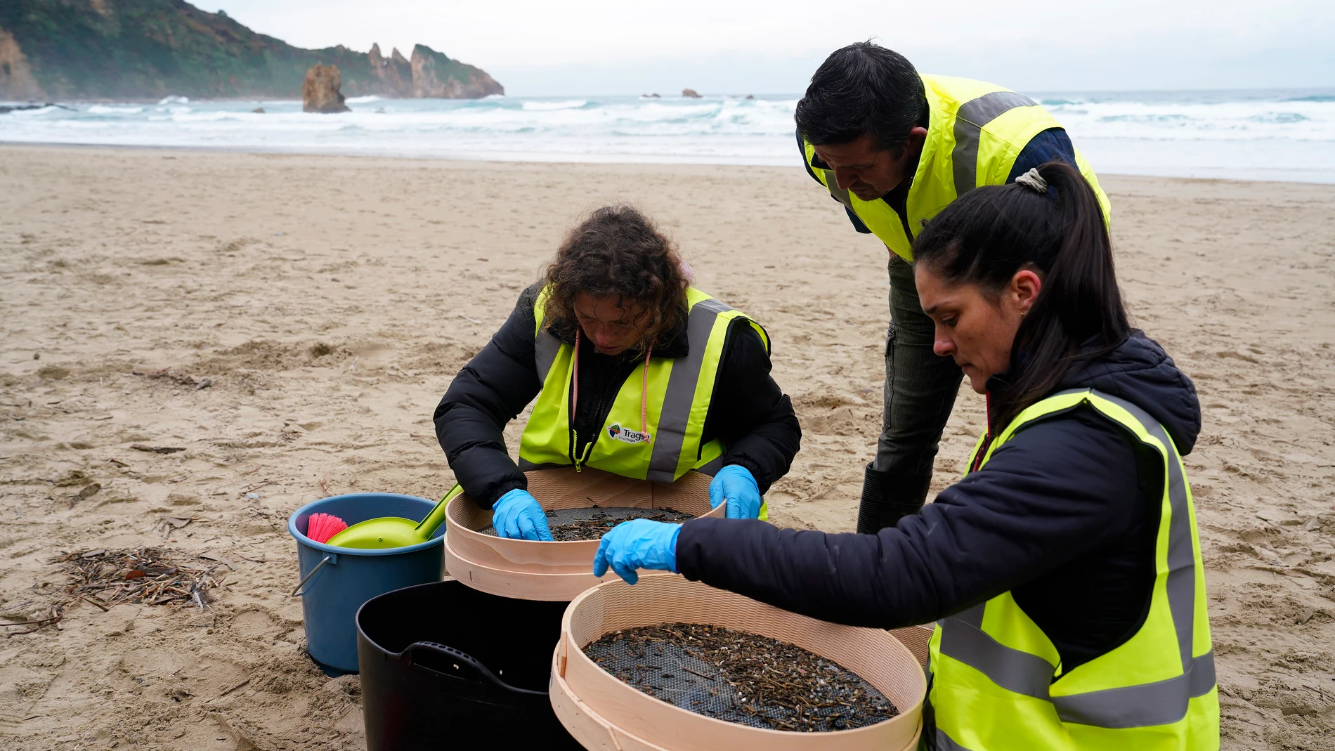 PLAYA DEL AGUILAR (ASTURIAS), 09/01/2024.- Operarios retiran los pellets o bolitas para fabricar plástico que aparecen en las playas de Asturias, tras la caída de un contenedor de un barco el pasado diciembre, esta mañana enla playa asturiana del Aguilar. EFE/Paco Paredes