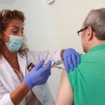 Una sanitaria vacuna a un hombre contra la gripe