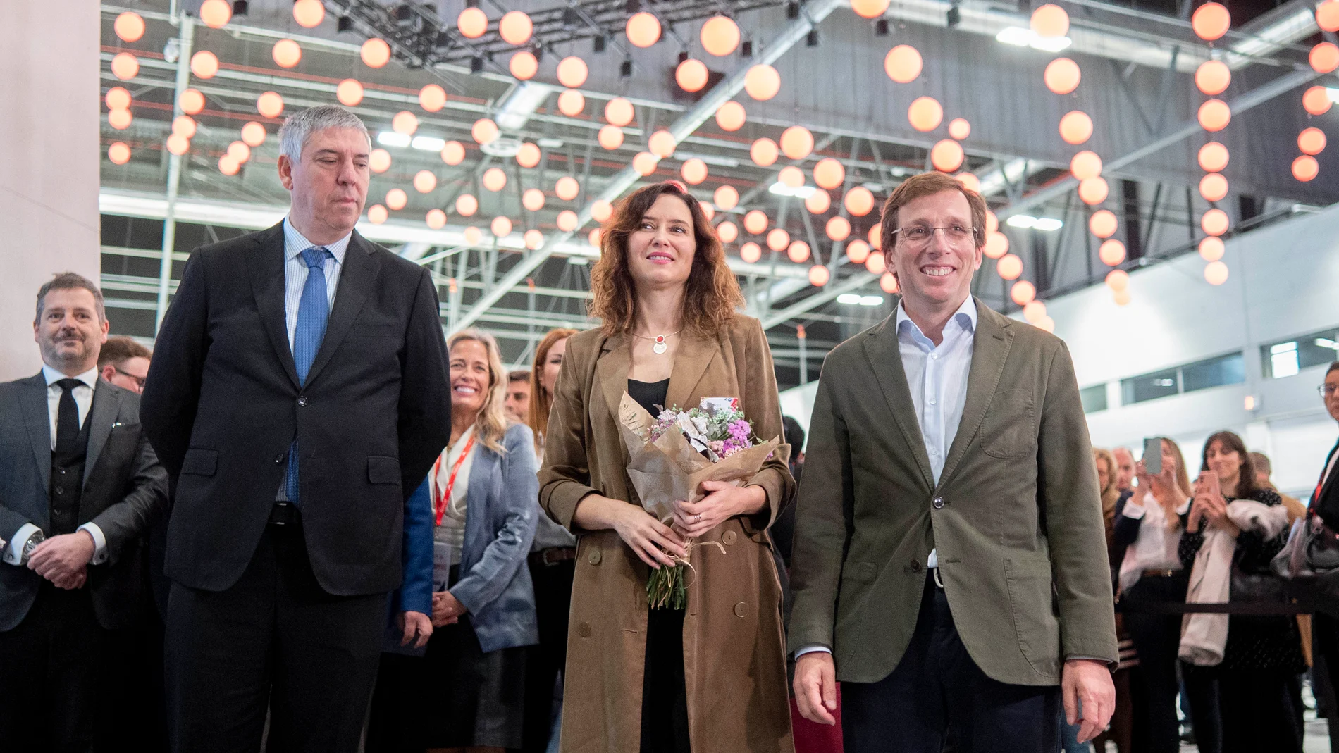 La presidenta de la Comunidad de Madrid, Isabel Díaz Ayuso (c), y el alcalde de Madrid, José Luis Martínez-Almeida (1d), a su llegada a la celebración del Día de Madrid en Fitur 2024, en IFEMA Madrid, a 26 de enero de 2024, en Madrid (España). El stand de la Comunidad de Madrid es un espacio de casi 1.500 metros cuadrados de superficie, construido con materiales cien por cien reutilizables. En el diseño destaca una cubierta móvil formada por luminarias de diferentes colores que permite adecua...