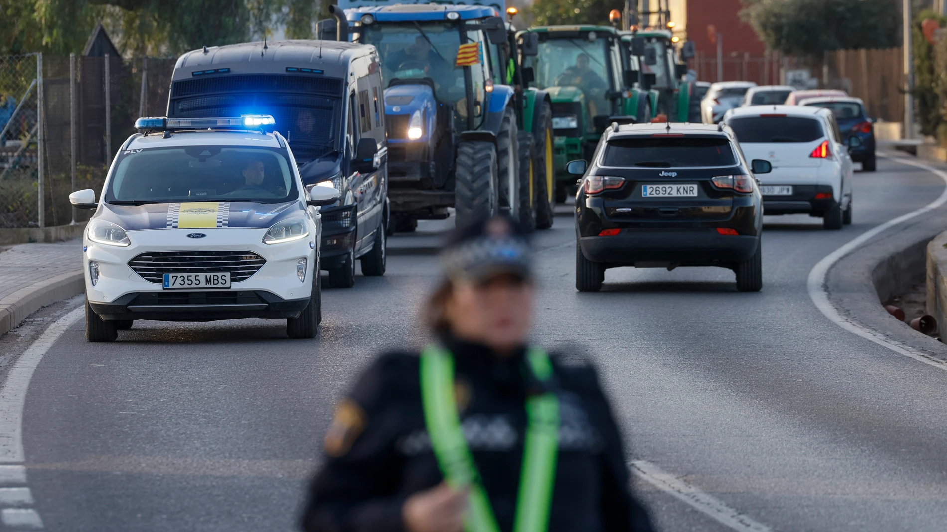 GRAFCVA8220. VALENCIA, 08/02/2024.- Una columna de tractores circula escoltada por la policía por el camino de Moncada cuando las manifestaciones de agricultores con tractores han causado este jueves por la mañana retenciones en la A-7 a la altura de Torrent (Valencia) para coger la A-3, y en la Ronda Norte de València. EFE/Kai Försterling