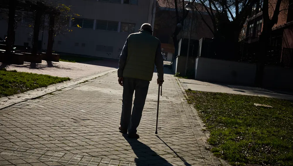 Mayores jubilados de la tercera edad pasean y toman el sol en un parque de Madrid.