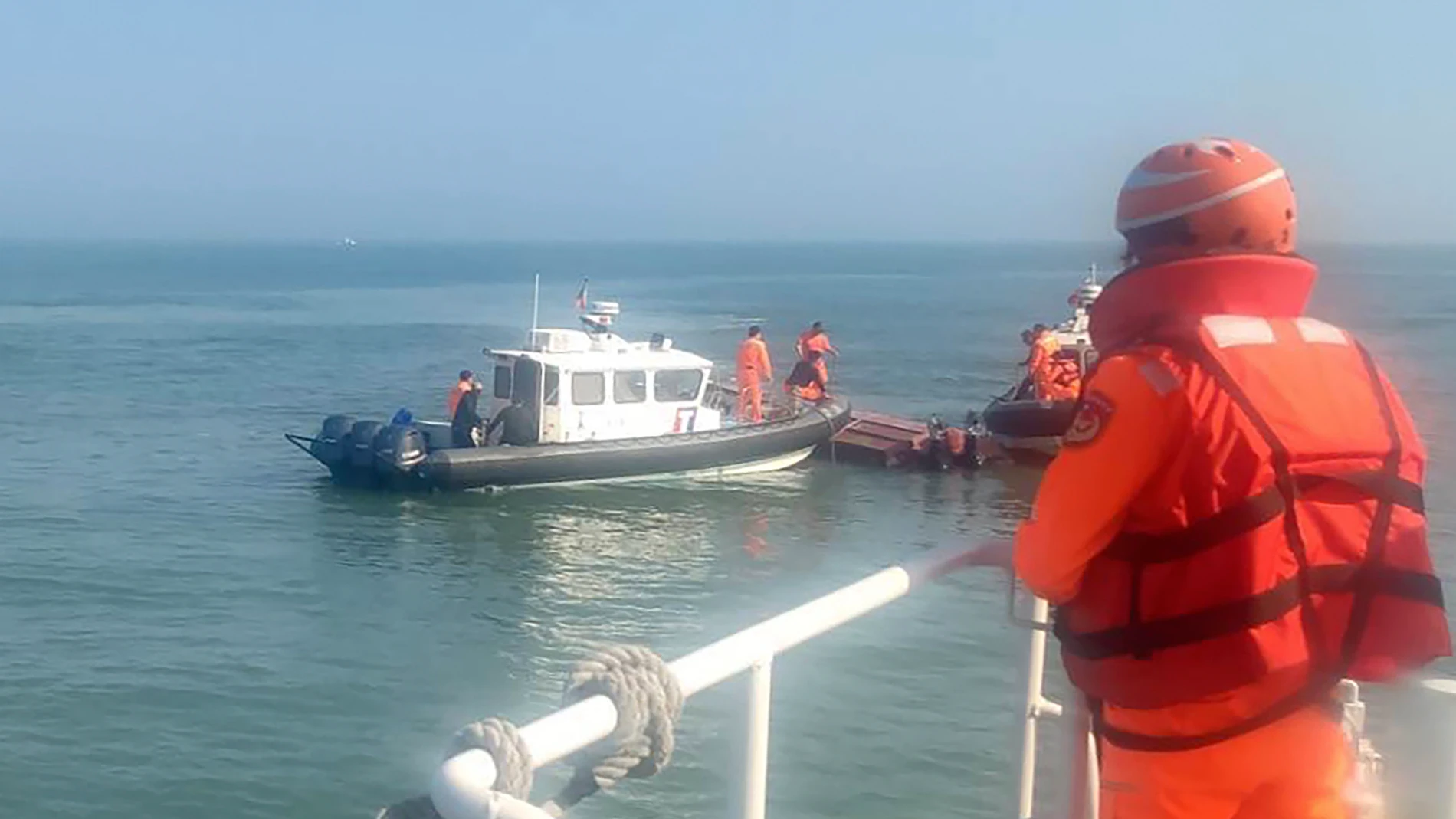 In this handout photograph provided by Taiwan Coast Guard Administration, Taiwanese coast guards inspect a vessel that capsized during a chase off the coast of Kinmen archipelago in Taiwan, Wednesday, Feb. 14, 2024. The unnamed vessel had been sailing about one nautical mile off the coast of an islet of Kinmen island and was trespassing, said Taiwan’s Coast Guard Administration. Four fishermen fell into the water and two survived and are in “good shape,” while resuscitation efforts on the oth...