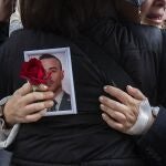 Una familiar sostiene una foto de uno de los agentes fallecidos a la salida del funeral